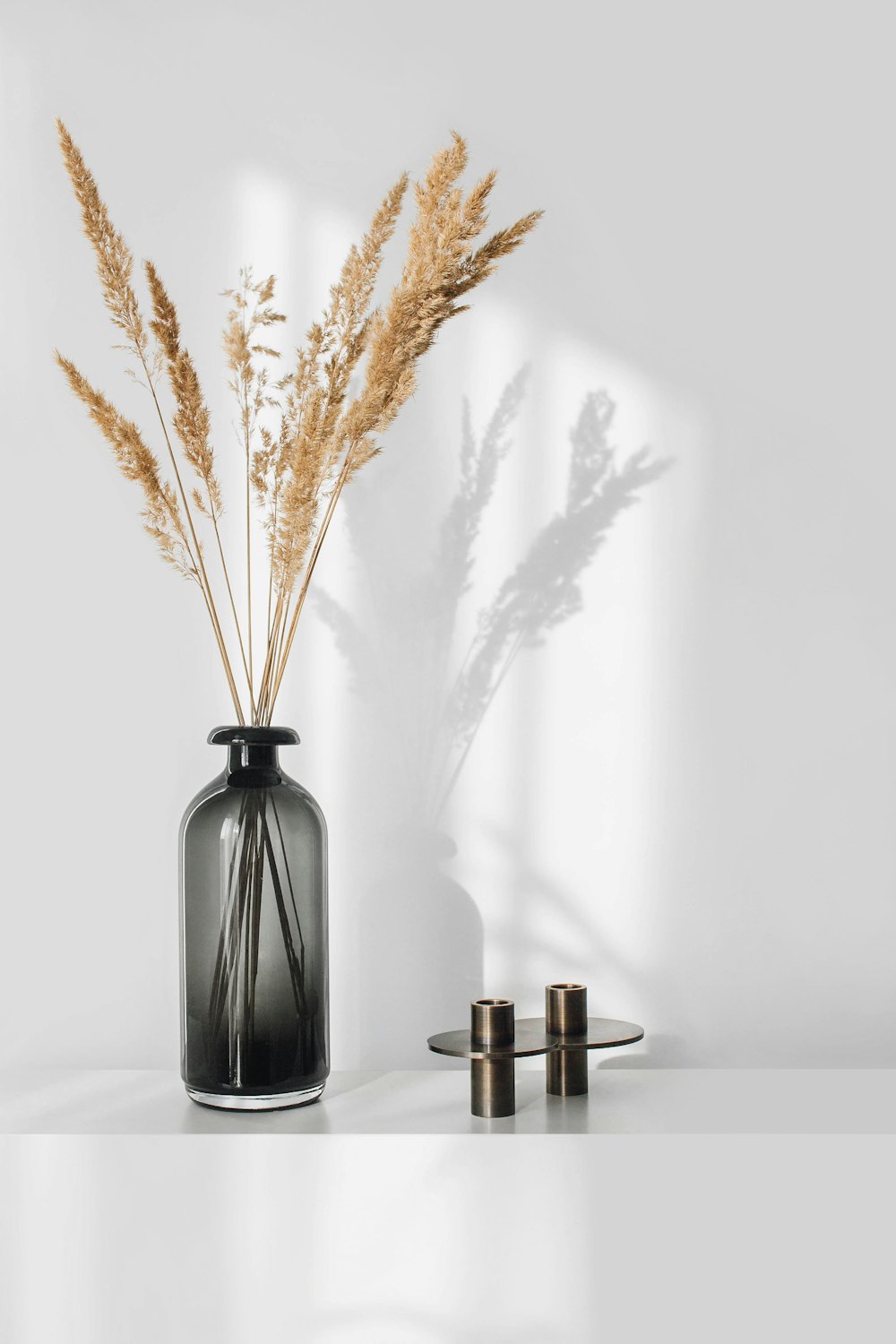 a black vase with some dry grass in it