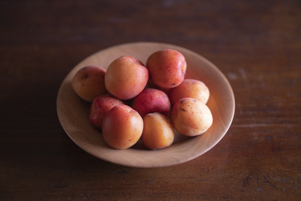A bowl of peaches on a wooden table