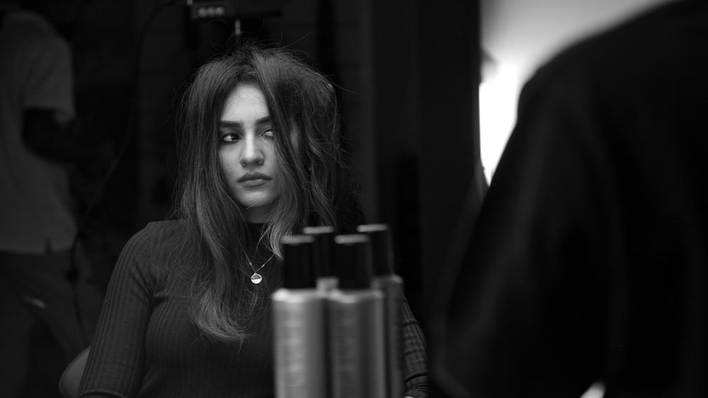 a woman with long hair sitting in front of a mirror