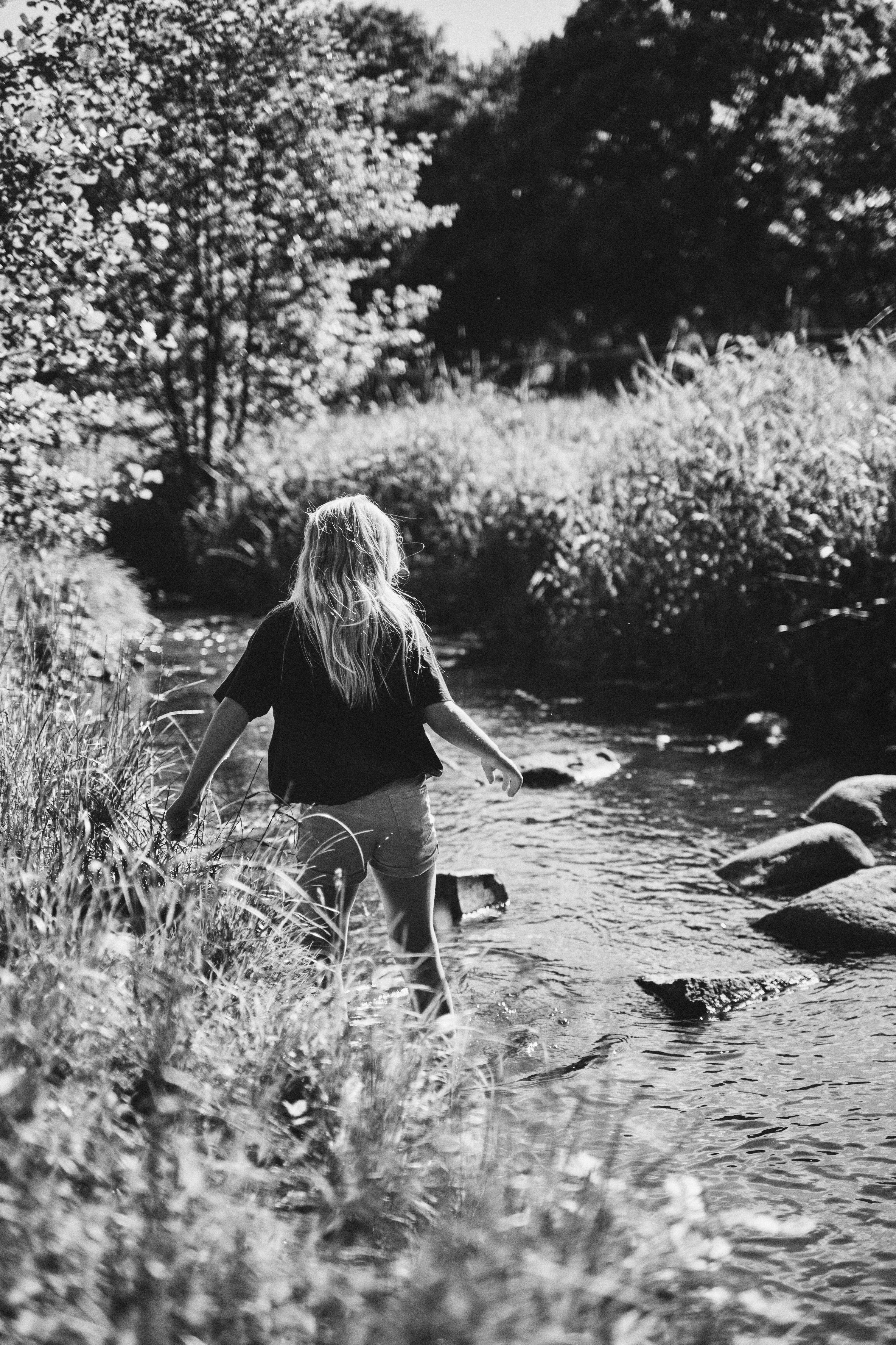 Une femme traversant une rivière à côté d’une forêt