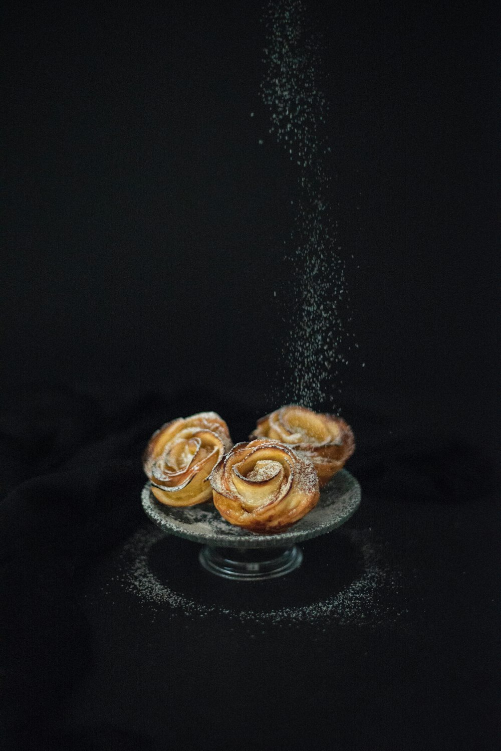 a plate of cinnamon buns sprinkled with powder