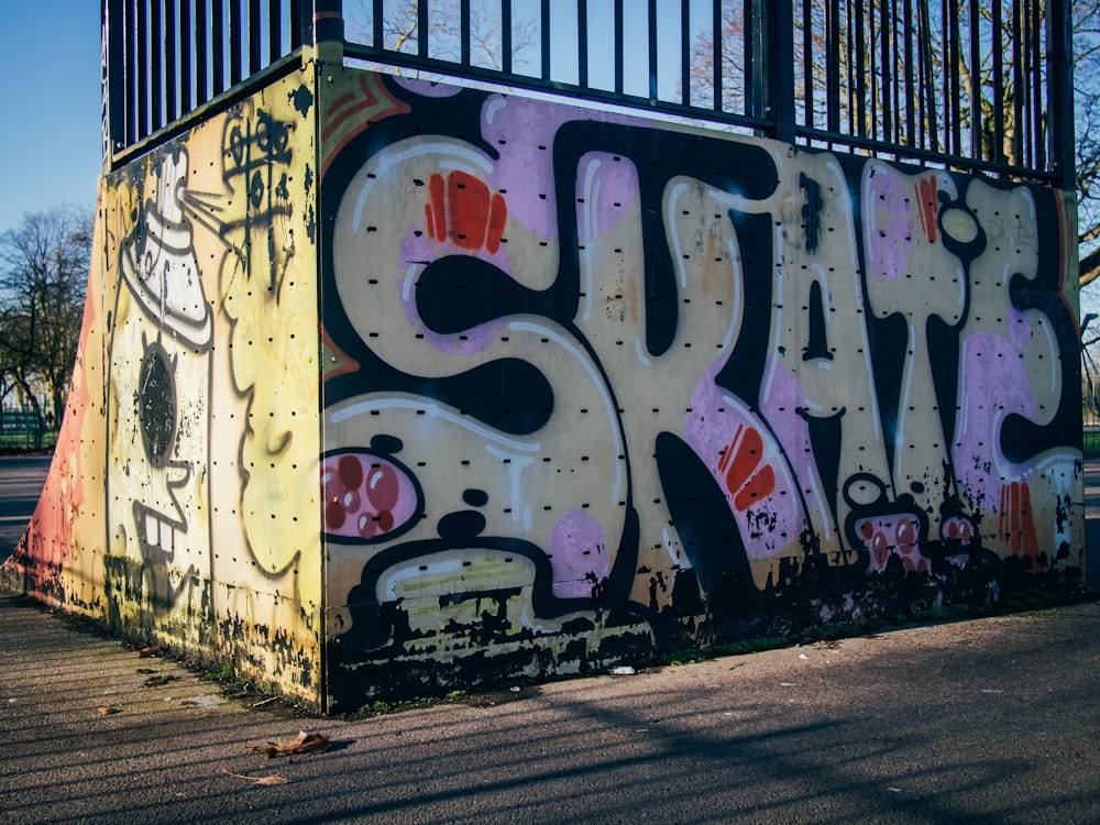 a wall covered in graffiti next to a fence