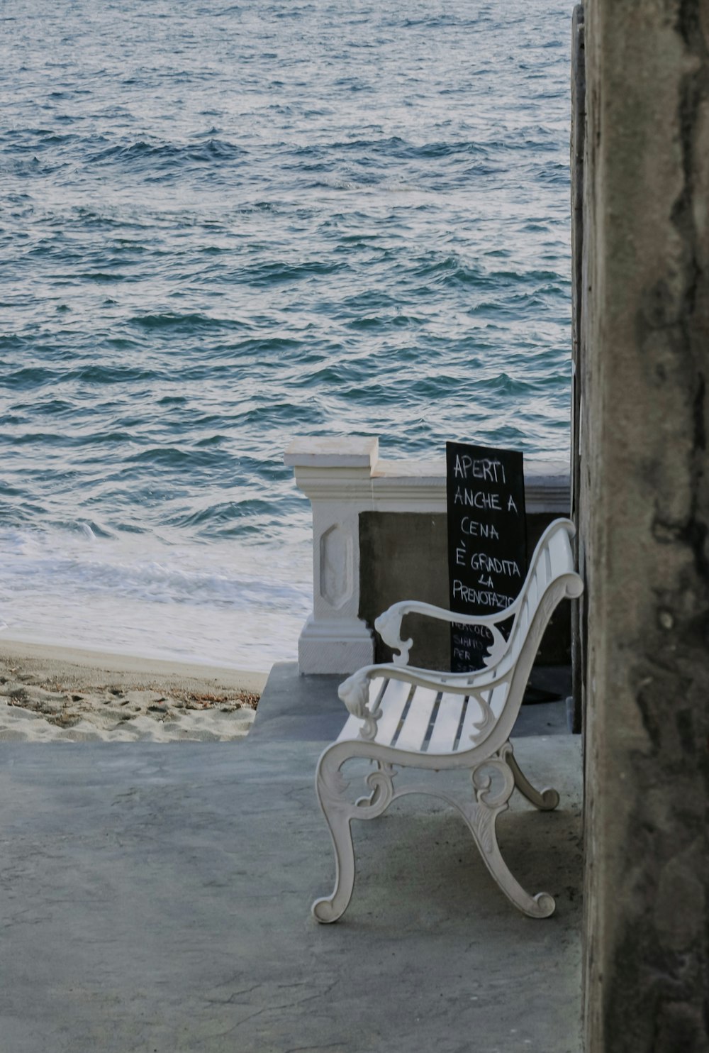 un banc blanc assis au sommet d’une plage de sable