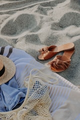 A colorful striped beach bag filled with a sunhat and sunglasses on a wooden boardwalk.