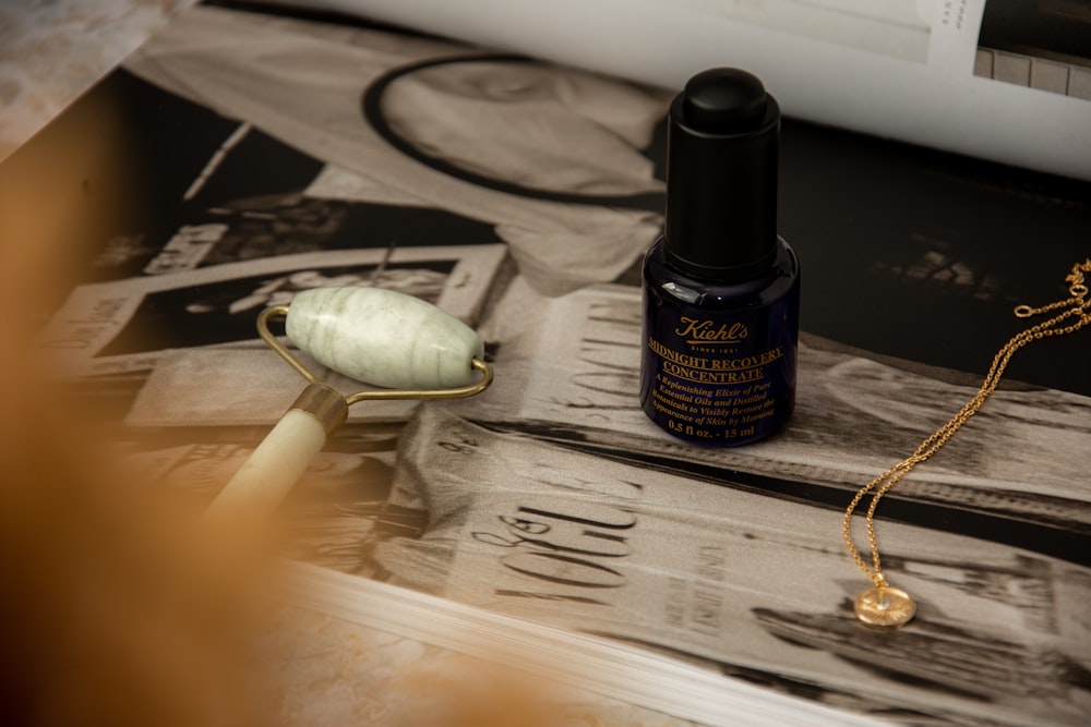 a close up of a bottle of perfume next to a necklace