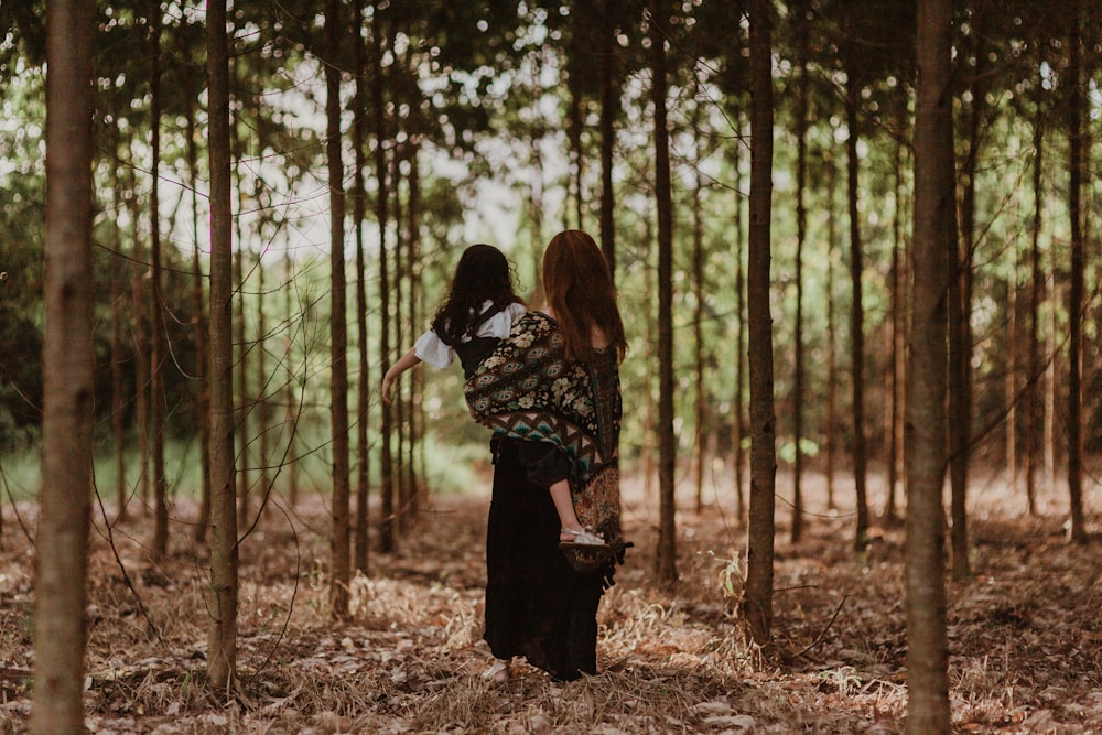 a woman carrying a child in a forest