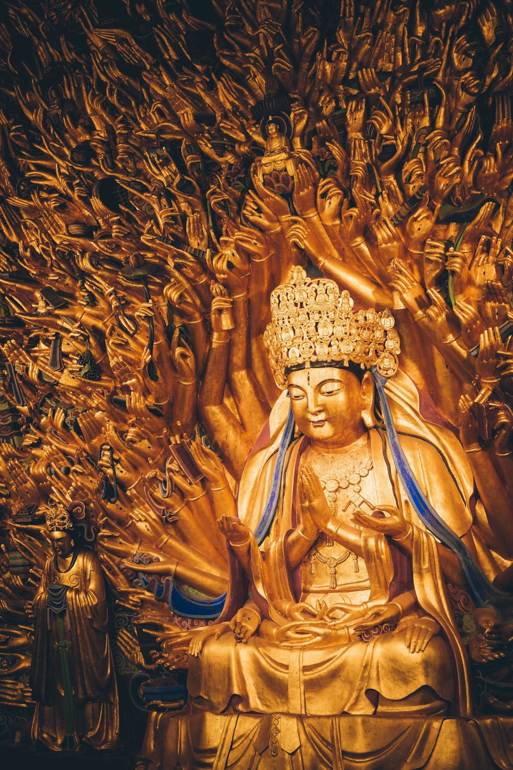 a golden buddha statue surrounded by golden hands