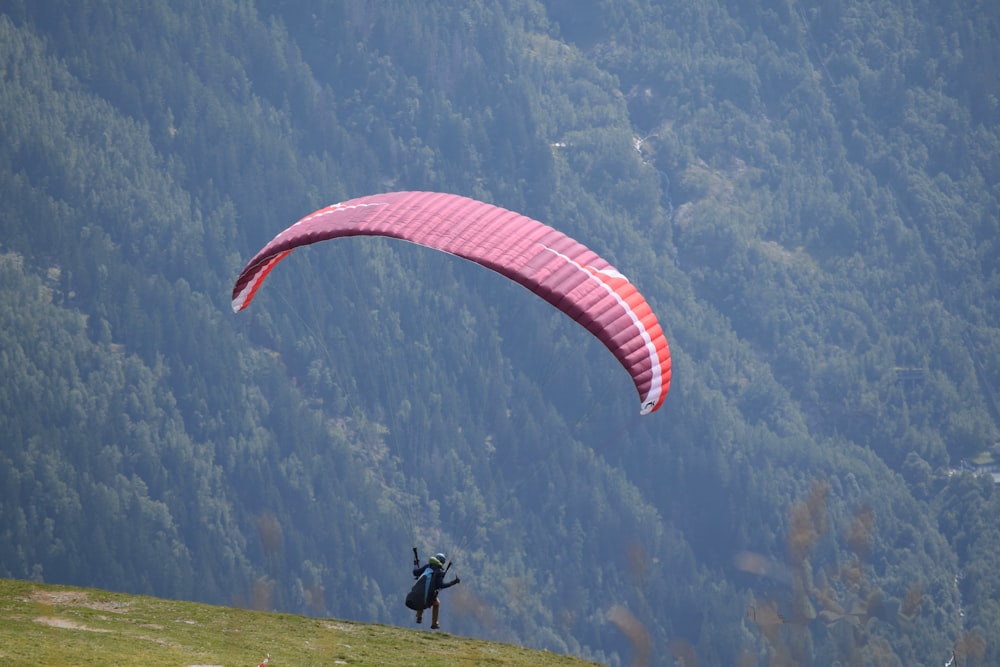 a person paragliding over a lush green hillside