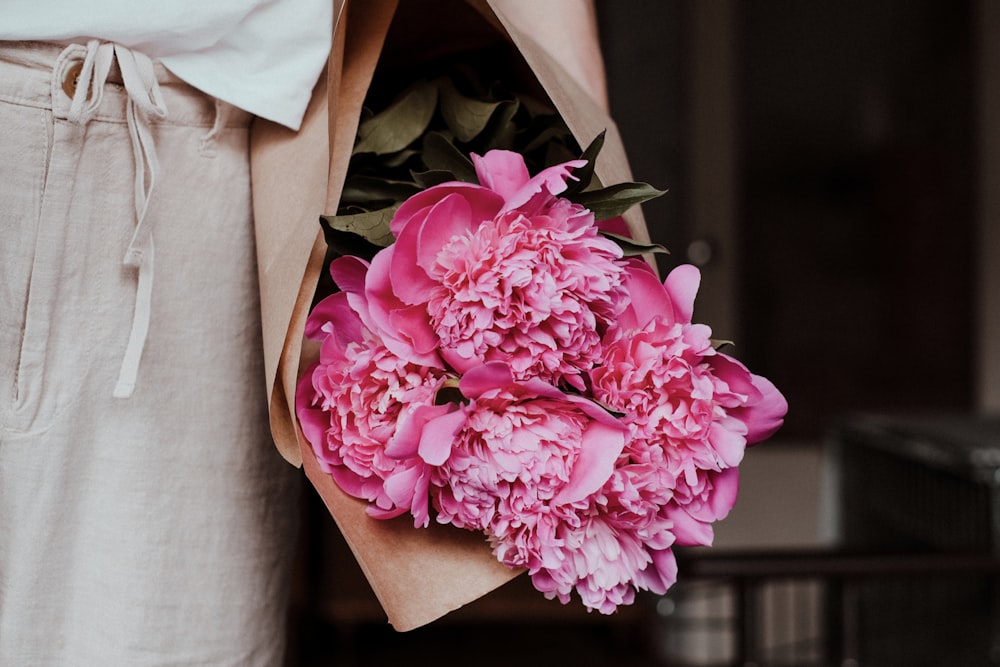 a person holding a bouquet of pink flowers