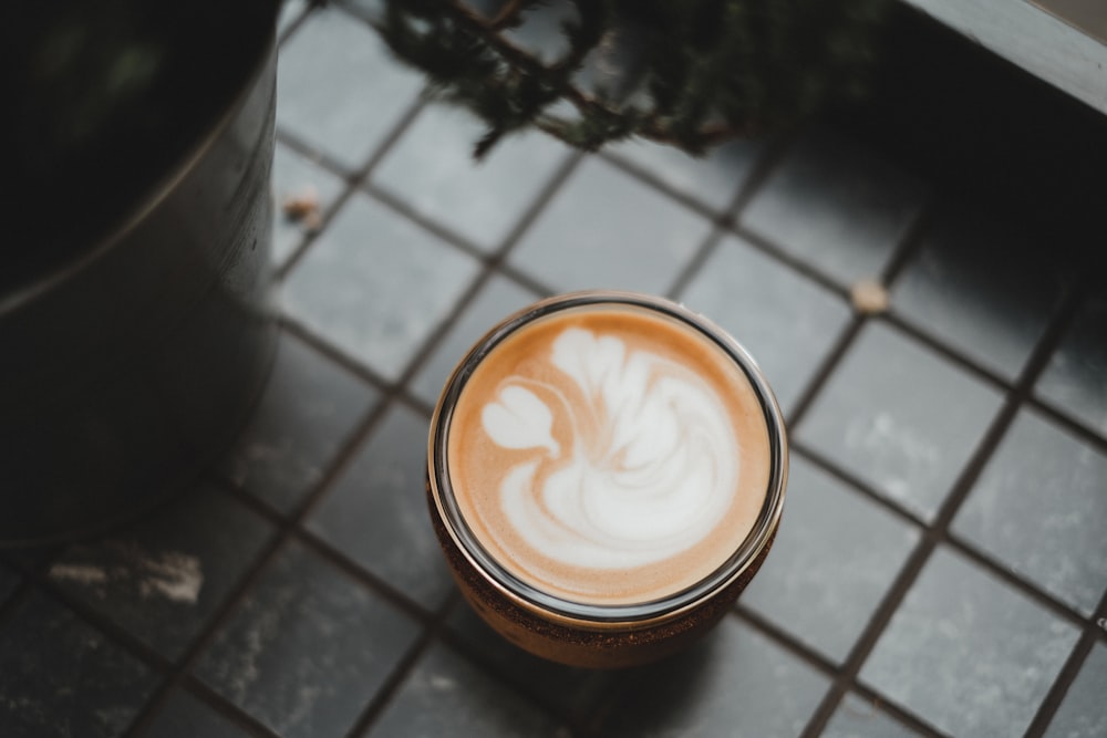 a cup of coffee sitting on top of a tiled floor