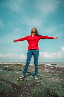 a woman standing on a rock with her arms outstretched