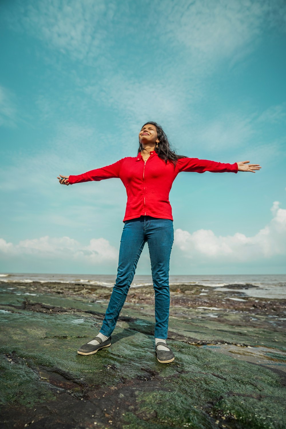 a woman standing on a rock with her arms outstretched