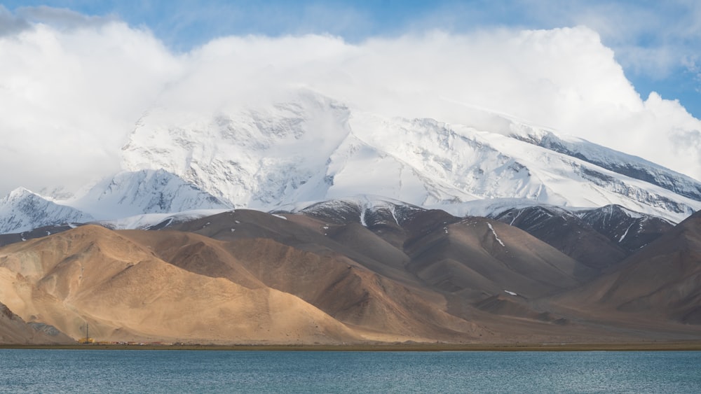 una grande montagna coperta di neve accanto a uno specchio d'acqua