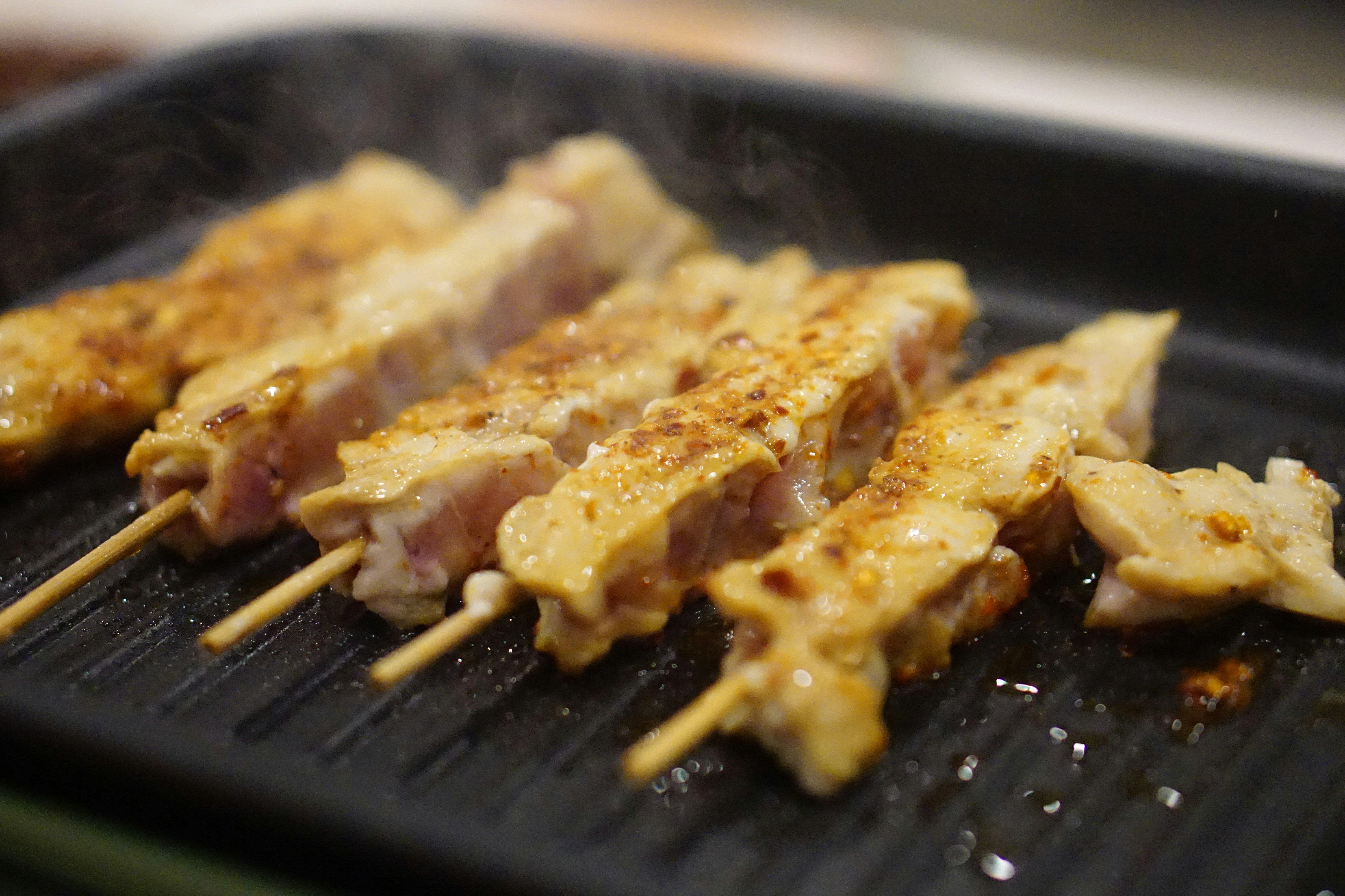 Chicken skewers grilling on a stovetop.