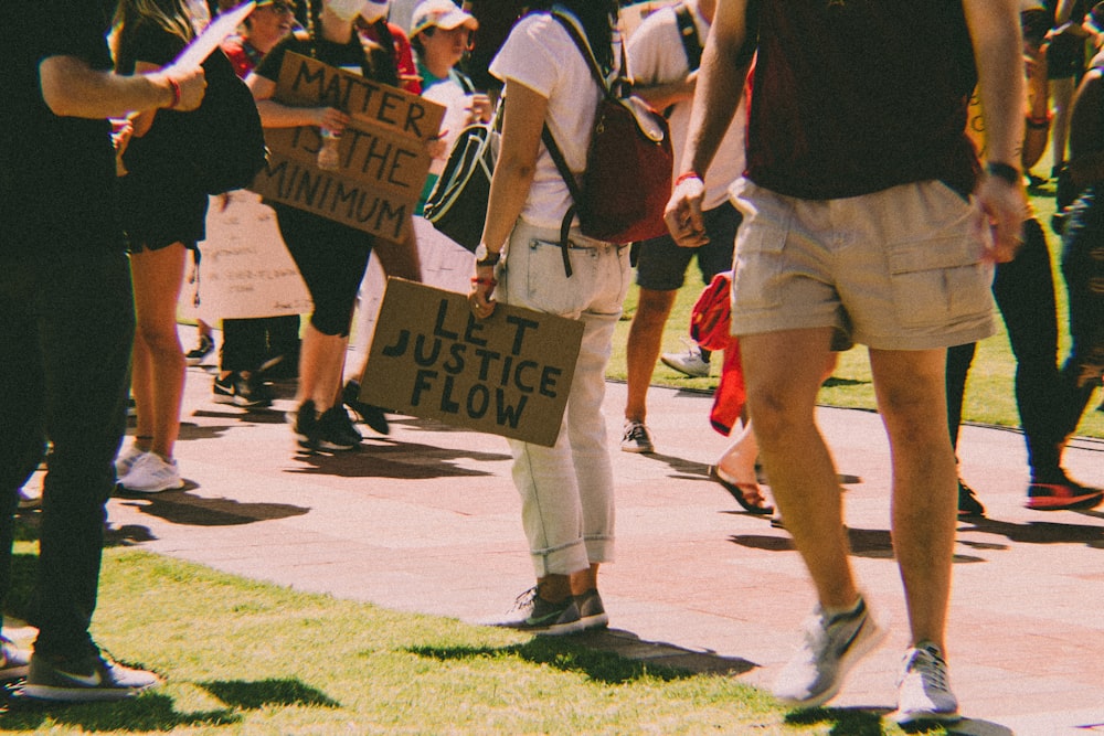 a group of people standing on a sidewalk holding signs