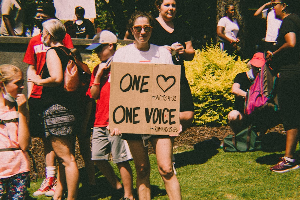 a man holding a sign that says one voice