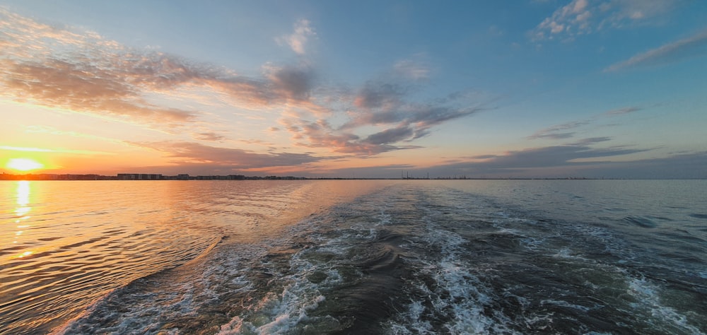 the sun is setting over the water as seen from a boat