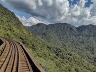 Railway tracks curving through a mountainous landscape under a clear blue sky.