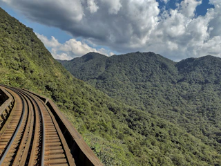Railway tracks curving through a mountainous terrain with workers inspecting the site.