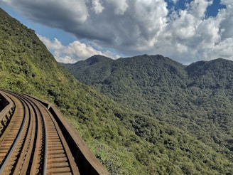 Railway tracks curving through a mountainous landscape under a clear blue sky.