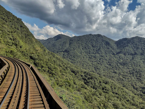 Railway tracks curving through a mountainous terrain with workers inspecting the site.