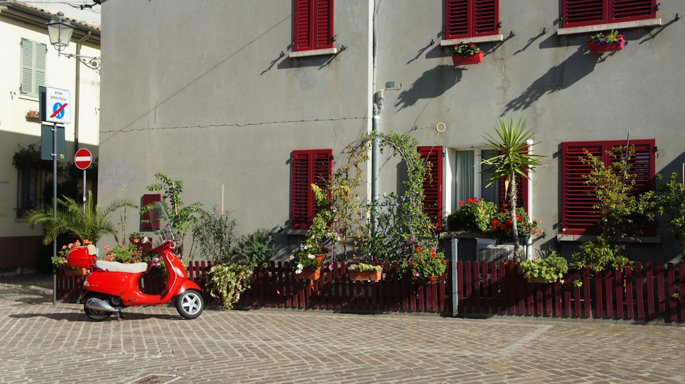 Ein Roller, der vor einem Gebäude mit roten Fensterläden geparkt ist