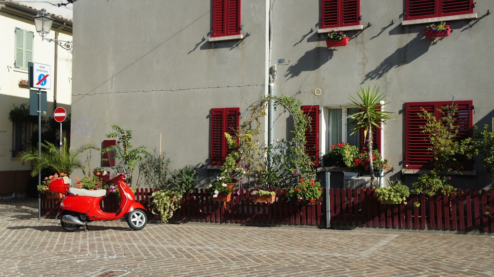 a scooter parked in front of a building with red shutters