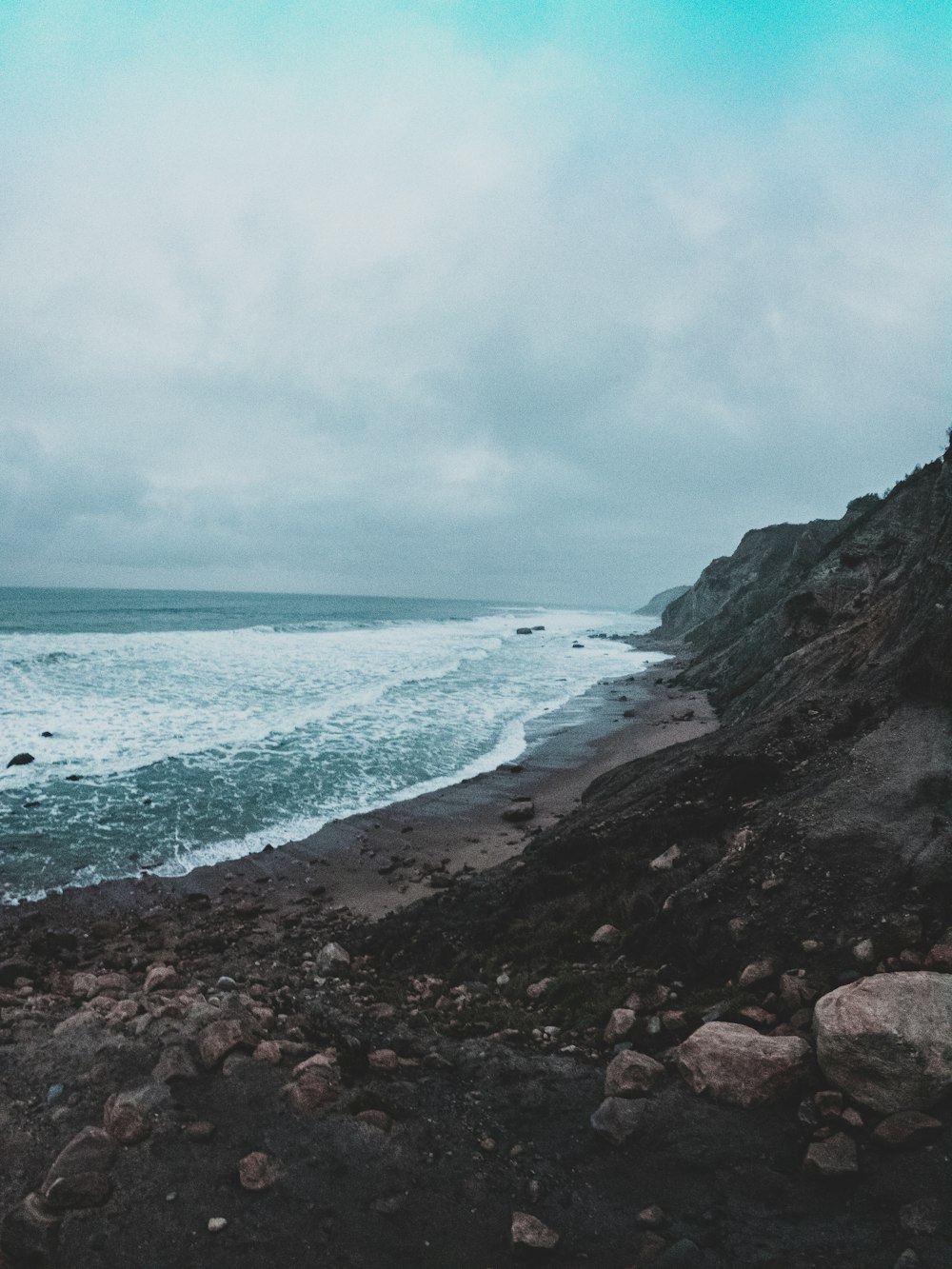 Eine Person, die an einem felsigen Strand neben dem Meer steht