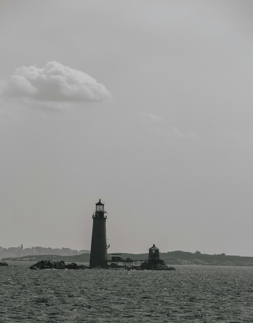 a black and white photo of a lighthouse in the ocean