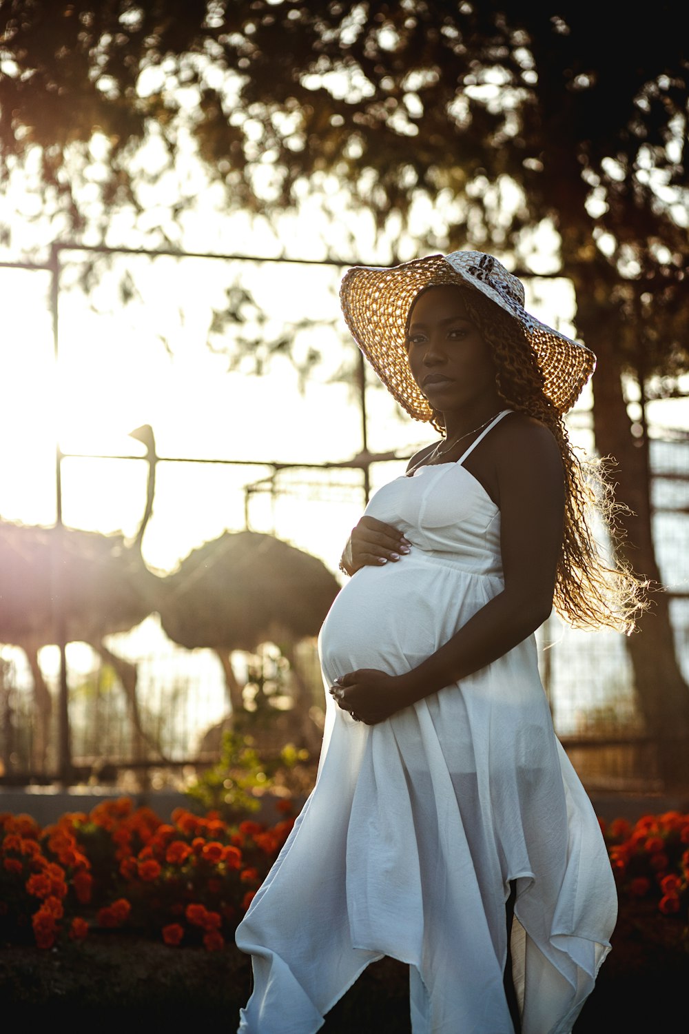 a pregnant woman wearing a white dress and a straw hat