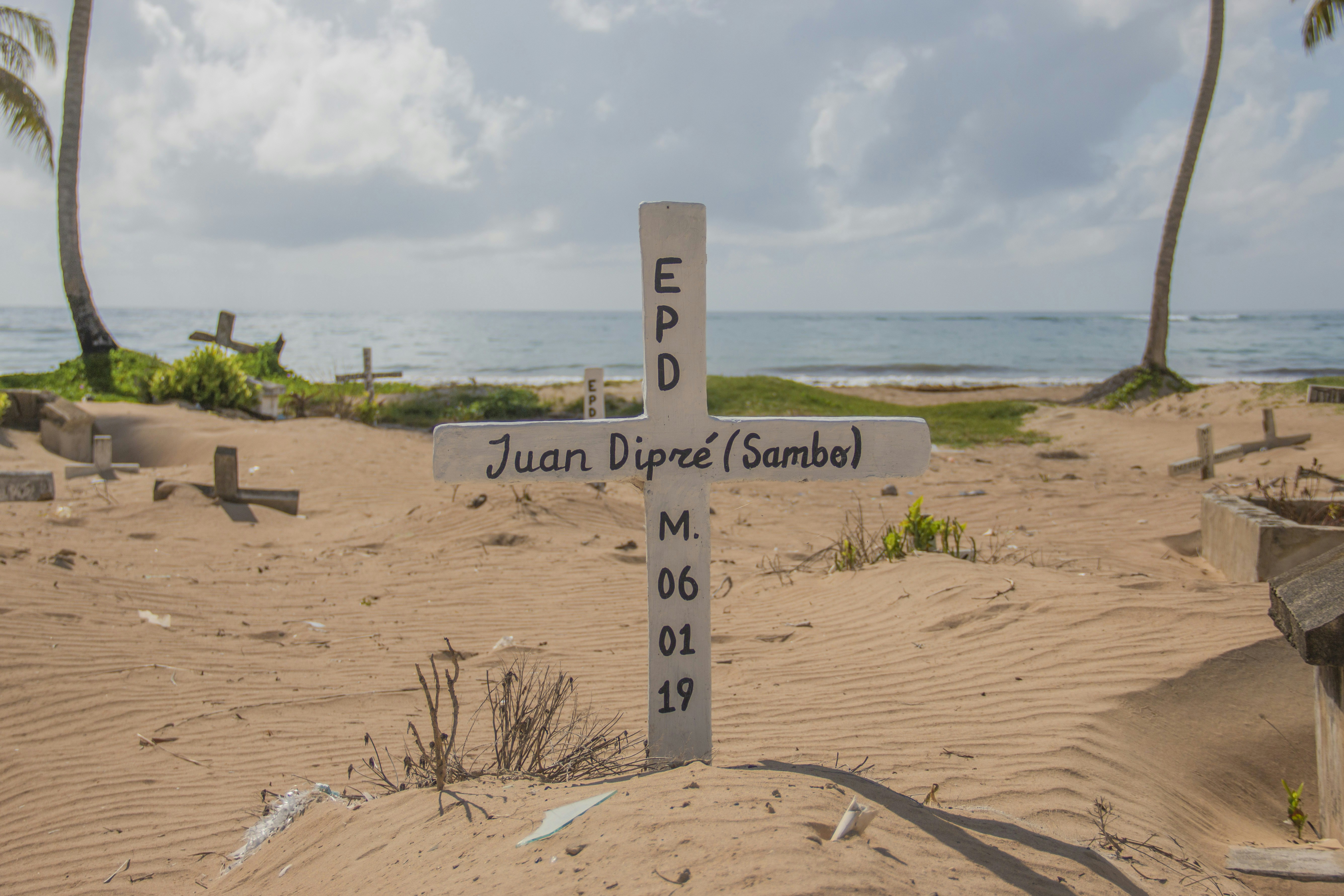 a cross on a sandy beach with palm trees in the background