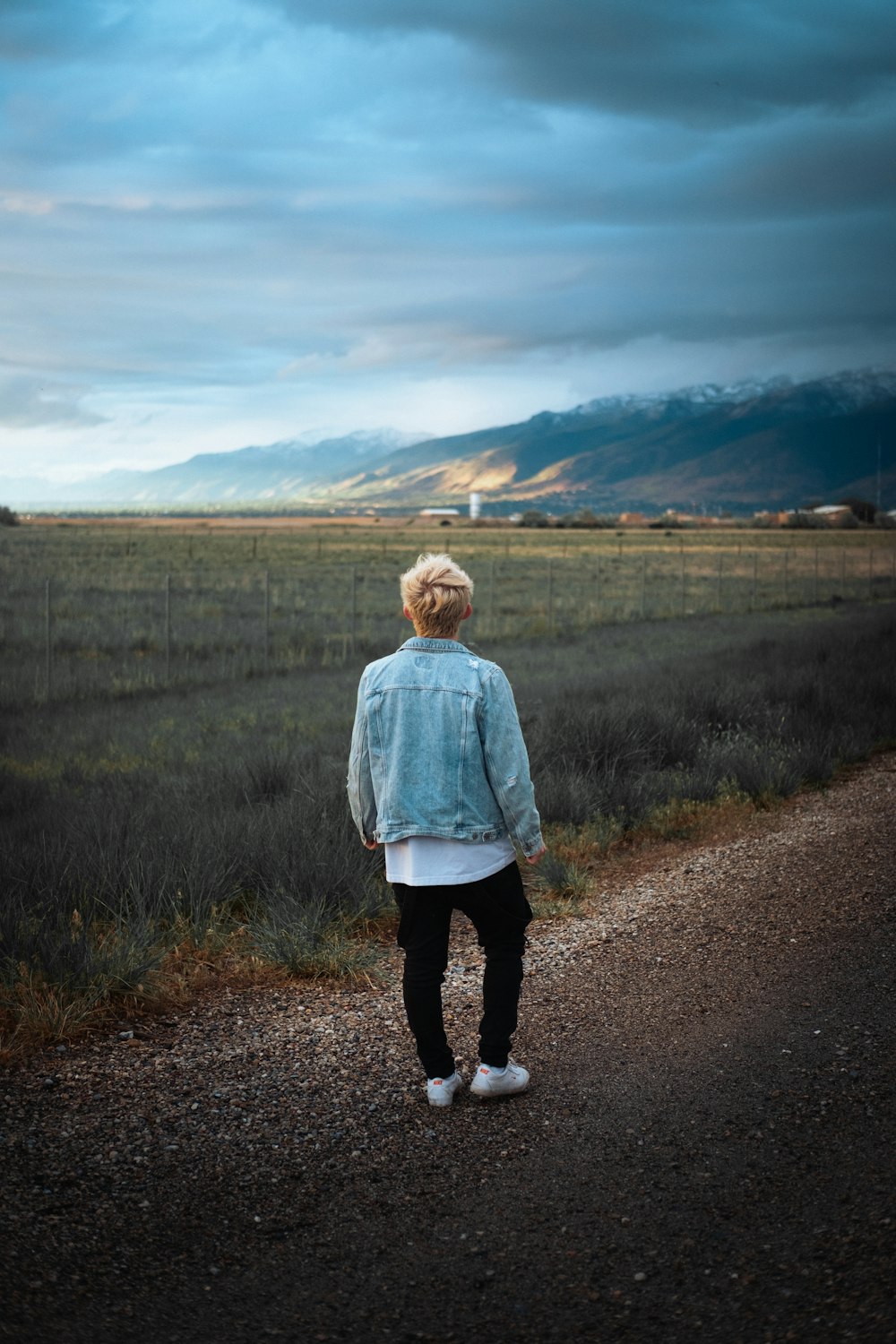 a person standing on a dirt road near a field