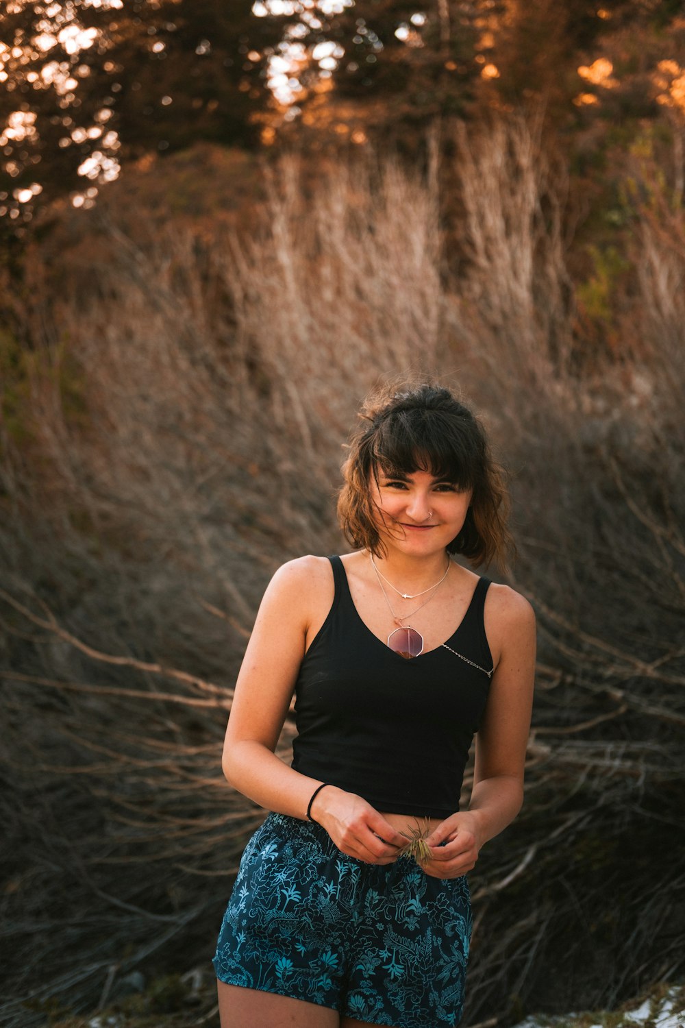 a woman standing in front of some bushes