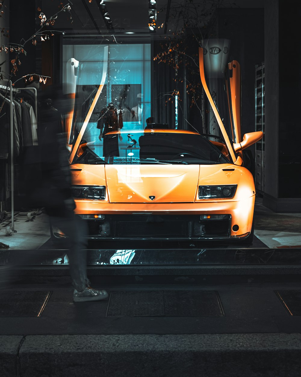 a man standing next to an orange sports car