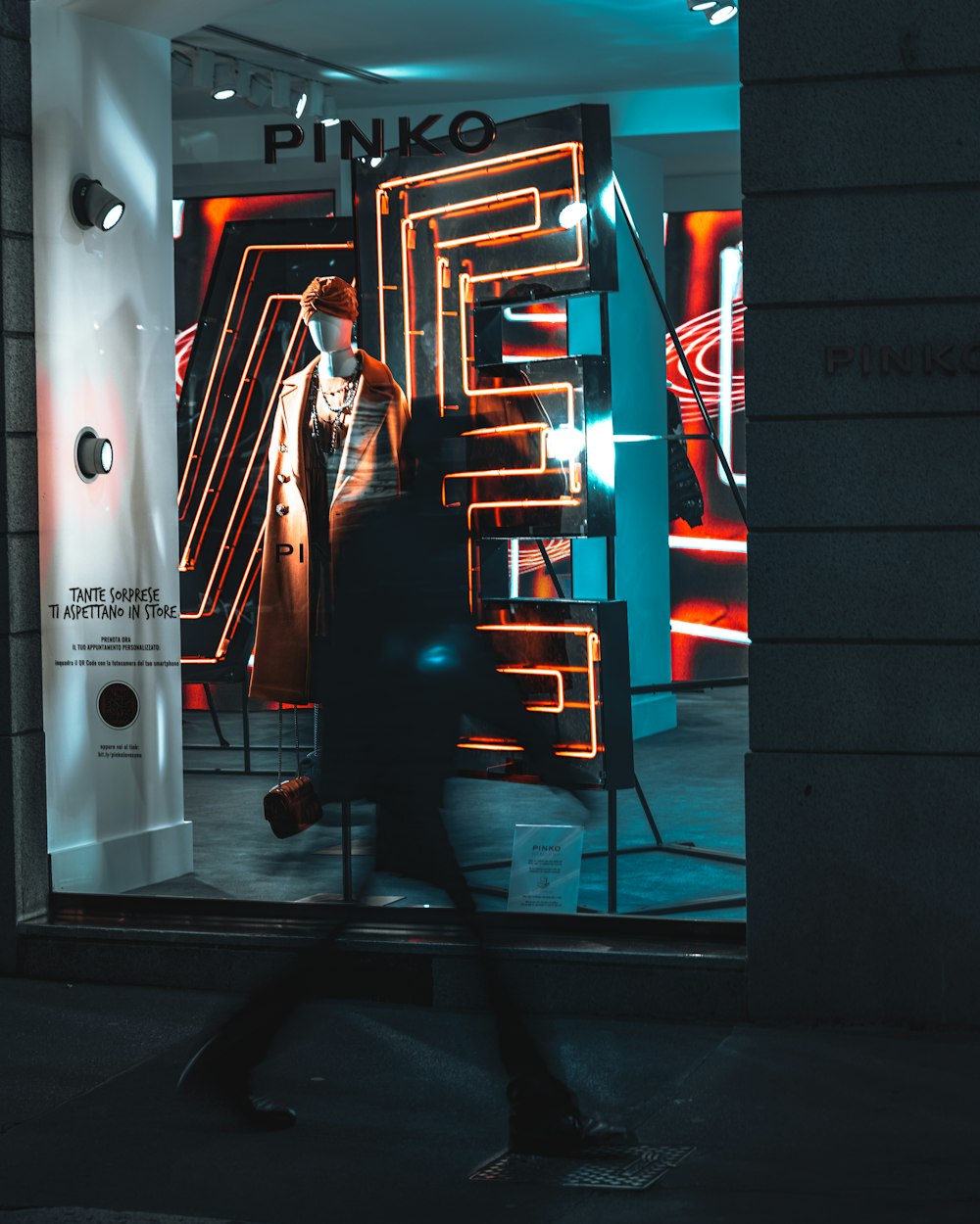 a man walking past a neon sign in a store window