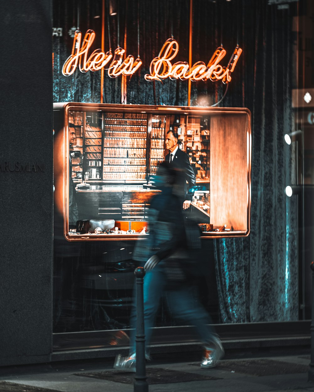 a woman walking down a street past a store front