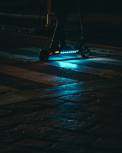 Sleek electric scooter in electric blue with glowing accents on a dark urban street at night