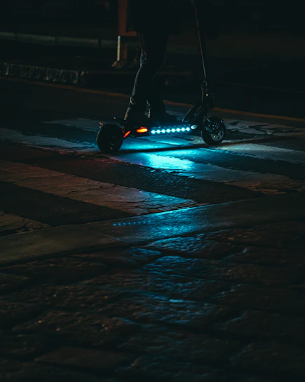 Sleek electric scooter in electric blue with glowing accents on a dark urban street at night