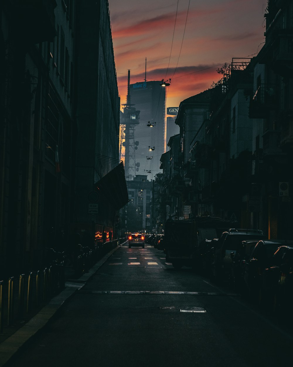 a dark city street with cars parked on both sides