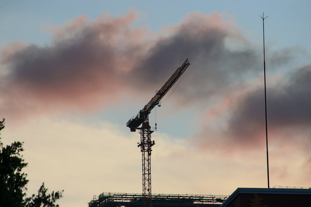 a crane is on top of a building under a cloudy sky