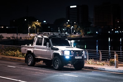 a white truck driving down a street at night