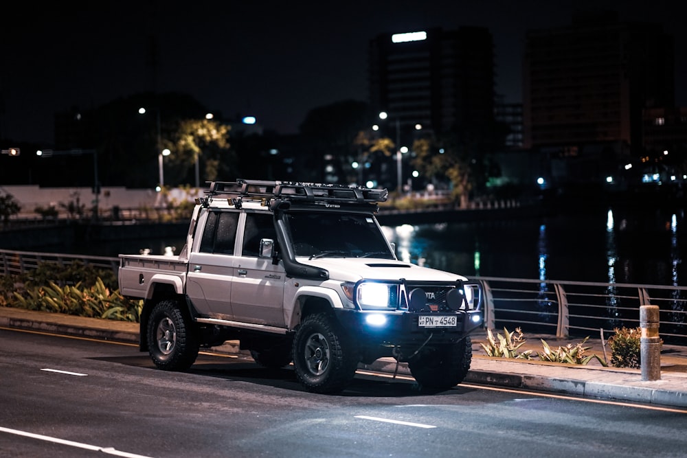 a white truck driving down a street at night