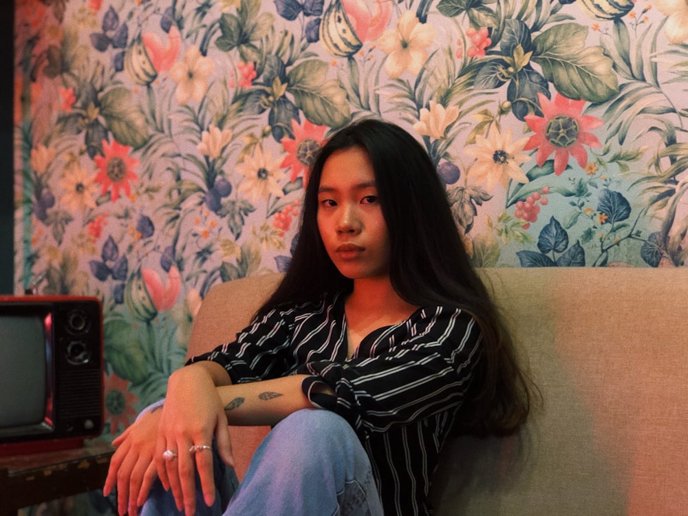 a woman sitting on top of a couch next to a tv