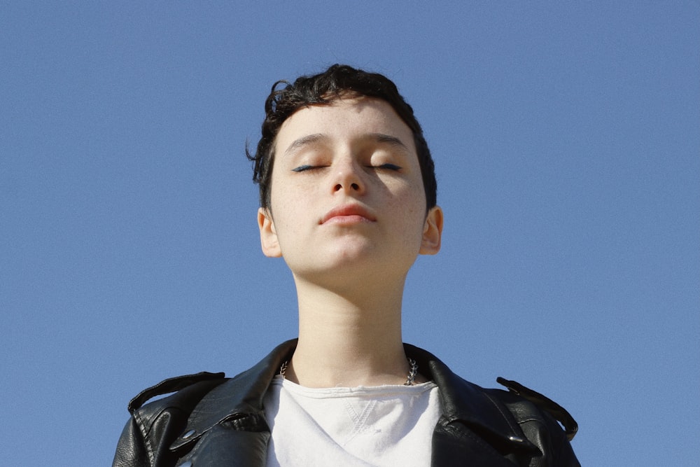 a boy in a leather jacket looking up into the sky