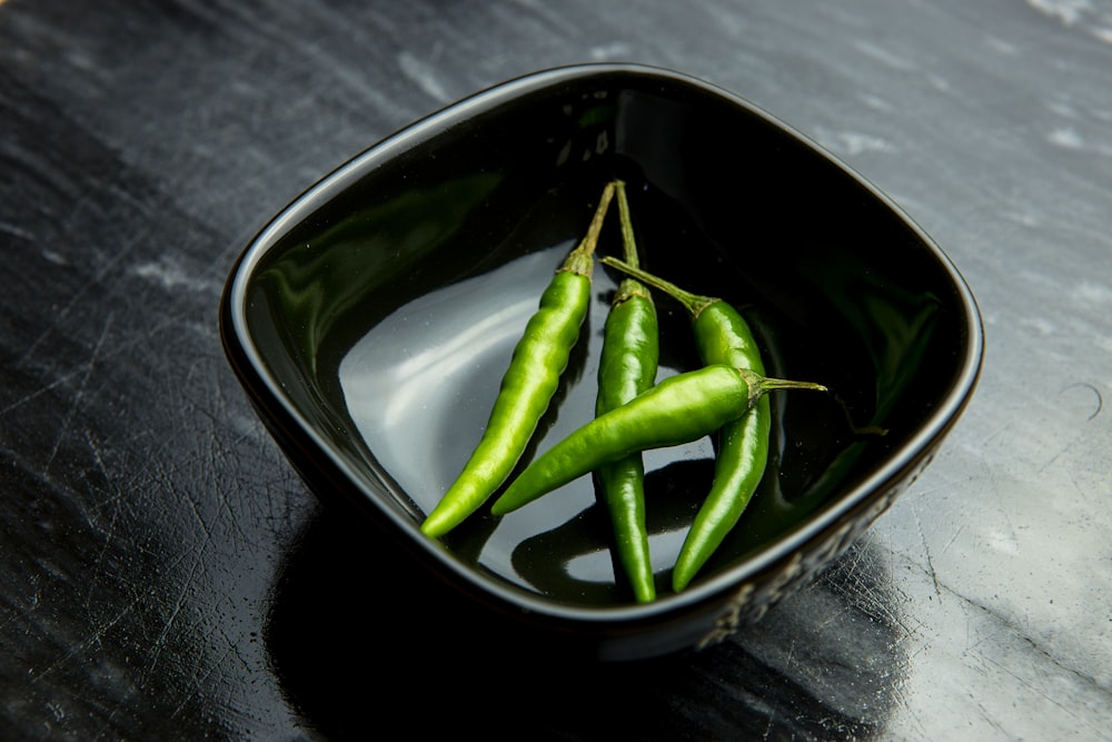 a black bowl filled with green peas on top of a table