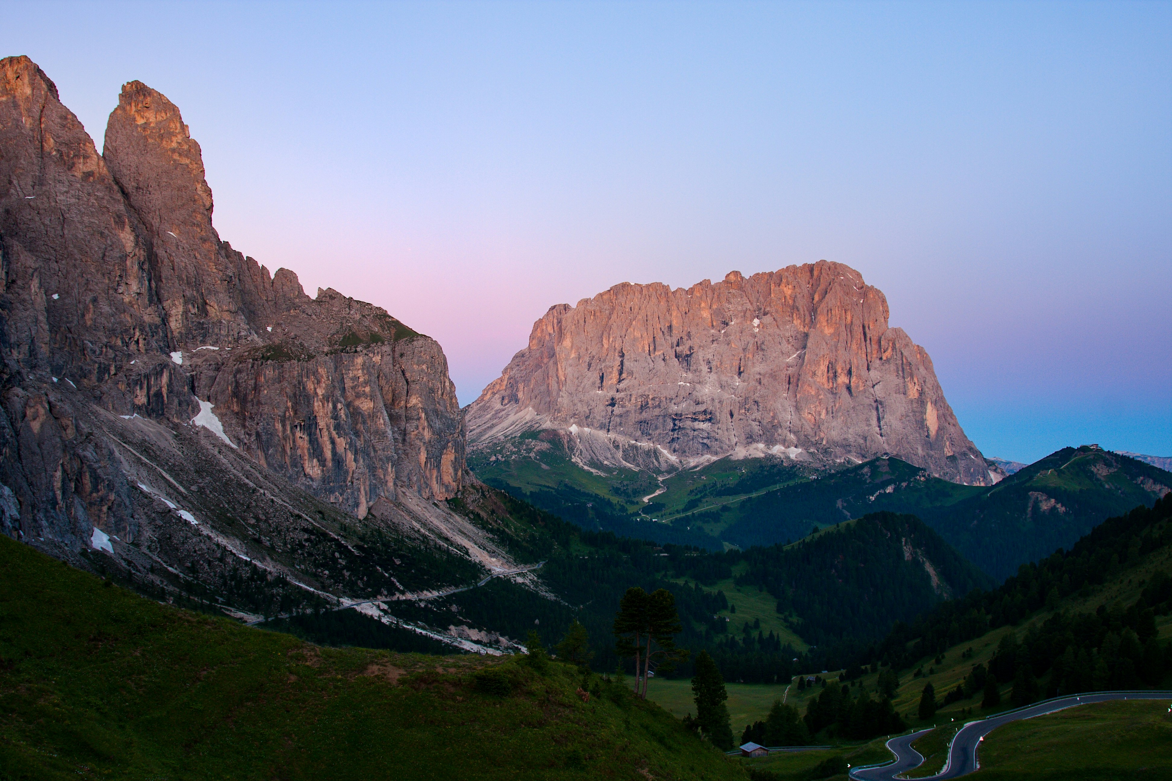Una catena montuosa con una strada tortuosa in primo piano