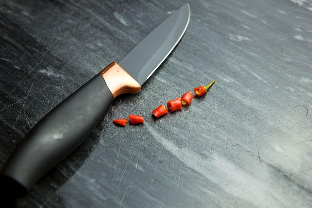 a knife and some red peppers on a table