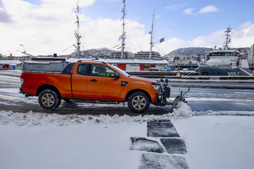 an orange pick up truck parked on the side of the road