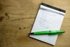 a notepad with a green pen on top of it