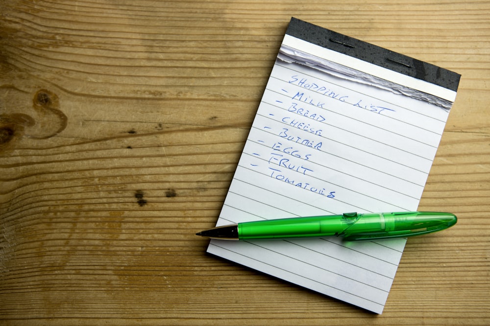 a notepad with a green pen on top of it